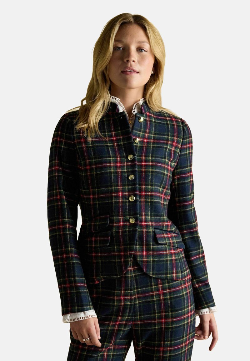 Plaid blazer in navy, green, and red tones, featuring gold buttons, tailored fit, and side pockets, paired with a white collared shirt.