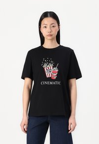 Zwarte katoenen t-shirt met een grafisch ontwerp van popcorn en een drankje. Het ontwerp bevat rood-witte strepen, met het woord "CINEMATIC" in het wit.