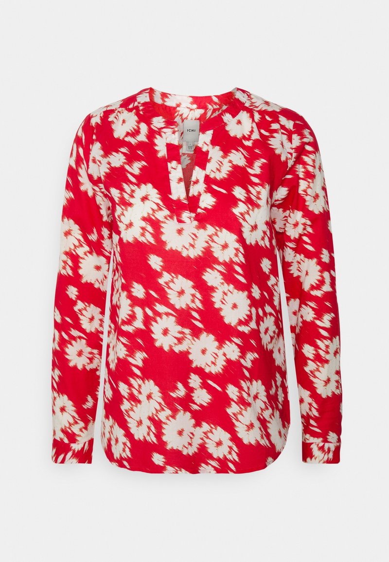 Blouse rouge à manches longues avec motif floral blanc et col en V fendu, présentée sur un fond uni.
