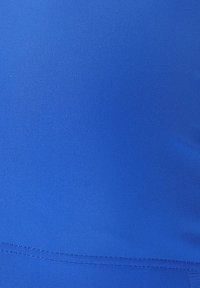 Ljust blått tyg med en strukturerad yta, slät finish och en sömdetalj längst ner. Materialet verkar elastiskt och kroppsnära.