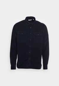 Laivastonsininen corduroy-paita, jossa on nappikiinnitteinen kaulus, kaksi rintataskua ja pitkät hihat. Edessä napillinen suljenta ja teksturoitu kangas.