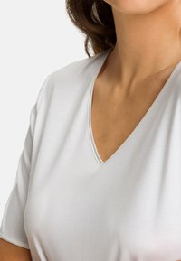 Vitt V-ringad t-shirt i en mjuk tygblandning, med korta ärmar och en subtil sömdetalj längs halsringningen.