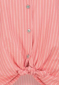 Pink short-sleeve shirt with vertical white stripes, featuring a twisted knot at the hem and silver buttons down the front.