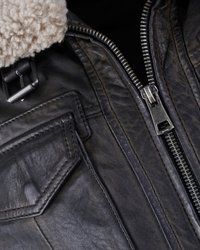 Zwarte leren jack met een schapenvachtkraag, voorzien van een zilveren rits, decoratieve zakken en textuurleer voor visuele interesse.