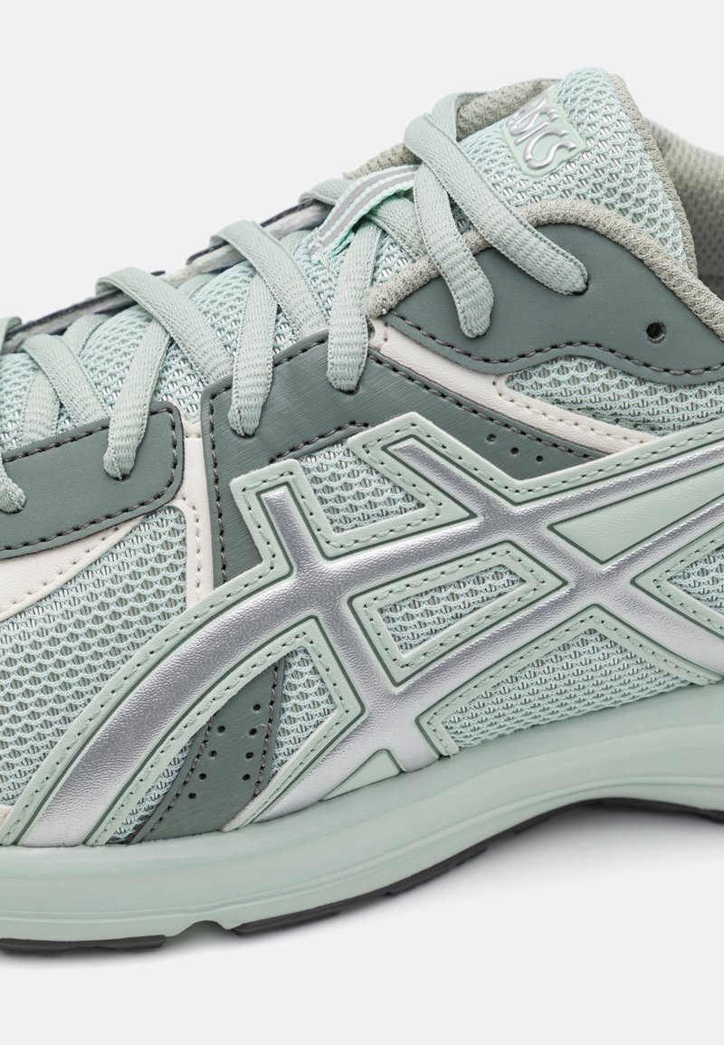 Hellgrüner Sportschuh mit Mesh-Obermaterial, silbernen Akzenten und gepolsterter Sohle. Verfügt über gemusterte Überzüge und Schnürdesign.