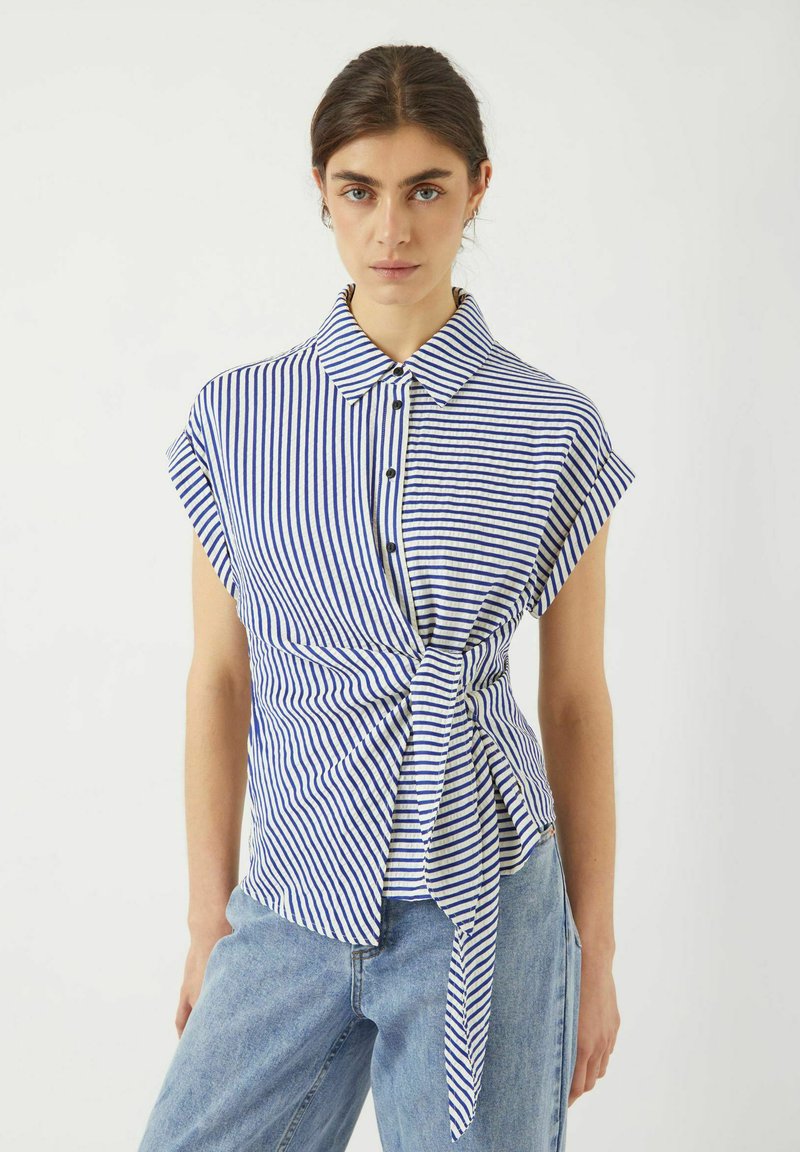 Camicia a maniche corte a righe blu e bianche con colletto e dettaglio annodato sul davanti, realizzata in un tessuto leggero.