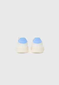 Hvite sneakers med en glatt tekstur, lyseblå hæl akenter og en tykk kremfarget såle. Minimalistisk design uten synlige mønstre.