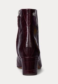 Bottine en cuir bordeaux à embossage crocodile avec un talon carré, fermeture éclair sur le côté et détail de logo. Texture lisse avec une finition polie.