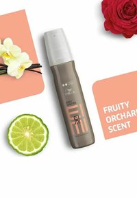Brun sprayflaska märkt "Body Crafter" med vit lock, i sällskap av en limeklyfta, blommor och text som indikerar fruktig fruktträdgårdslukt.