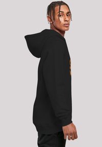 Sudadera negra con bolsillo delantero, con un diseño gráfico en naranja. Hecha de una tela suave, tiene un corte relajado y capucha con cordón.