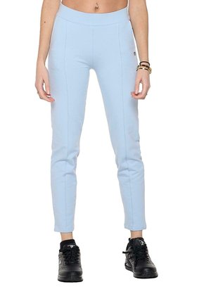 Modèle portant un pantalon ajusté bleu clair et des baskets noires, représenté de la taille aux pieds sur un fond blanc.