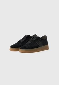 Baskets en daim noir avec un dessus texturé, un design à lacets, un panneau latéral noir lisse et une semelle en caoutchouc gomme.