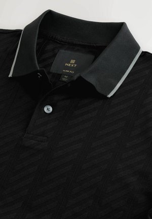 Polo shirt nera in vestibilità slim con un motivo a chevron testurizzato, dotata di patta con bottoni e bordo del colletto in grigio contrastante.