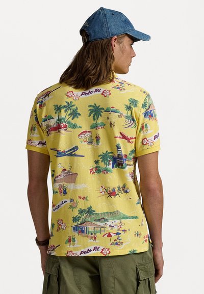 Camisa de manga corta amarilla con un colorido patrón tropical que incluye palmeras, escenas de playa y vehículos vintage.