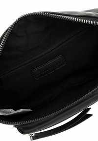 Borsa in pelle nera aperta per mostrare l'interno con rivestimento di tessuto, una tasca con cerniera e un'etichetta del marchio visibile all'interno.