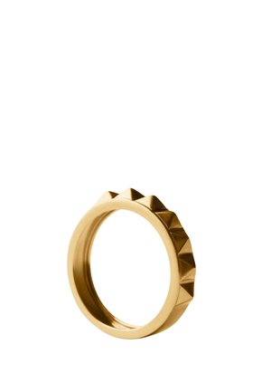 Anillo de metal color oro con una banda interior lisa y una fila de tachuelas en forma de pirámide espaciadas uniformemente en el borde exterior.