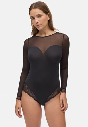 Bodysuit negro con un top de malla transparente de manga larga, escote corazón y borde de encaje en la parte inferior. Textura suave en toda la prenda.