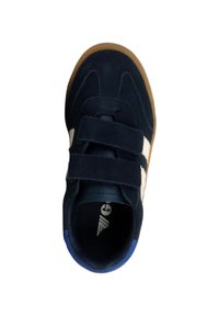 Zapato de gamuza azul marino con rayas blancas y dos cierres de velcro. Punta redondeada y suela de goma color caramelo. Detalle azul en el talón.