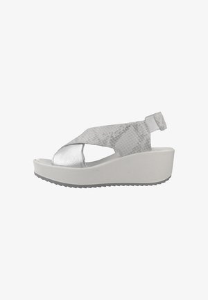 Sølv wedge sandaler med krydsrem-design, der har tekstureret materiale og en flad, hvid sål med grebdetaljer.