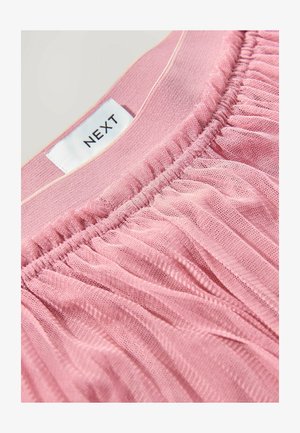 Vêtement élastique rose avec texture froncée, fabriqué dans un tissu doux et léger. L'étiquette affiche "NEXT" sur une étiquette cousue.