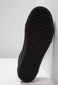 Sole di sneaker nera con un motivo geometrico texturizzato. Materiale in gomma con bordi arrotondati, senza marchi o decorazioni visibili.