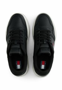 Sneaker nere con tomaia in pelle, punta perforata, accenti testurizzati e suola bianca. Presentano lacci neri e dettagli del logo in rosso e blu.