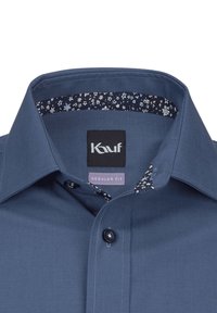 Camicia blu con vestibilità regolare, caratterizzata da un colletto interno a motivo. Ha una texture liscia e bottoni neri. L'etichetta riporta la scritta "Kauf."