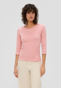 Lichtroze, geribbelde langemouwen top met een ronde halslijn en een gegolfde zoom. Het materiaal lijkt zacht en heeft een aansluitende silhouet.