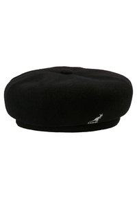 Beret de lana negra con forma circular y plana. Presenta un pequeño botón en la parte superior y un logotipo blanco en el lateral, mostrando una textura suave.