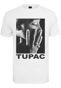 White cotton t-shirt featuring a large black and white portrait of a person with rings on their fingers and the word "TUPAC" in bold black letters.
