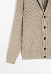 Beige Strickjacke mit V-Ausschnitt, langen Ärmeln und sechs schwarzen Knöpfen auf der Vorderseite. Strukturiert mit Rippenmuster.