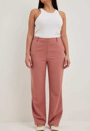 Pantalons ajustés rose clair avec un design à jambe droite, comprenant des poches latérales et une ceinture épurée, associés à un débardeur blanc.