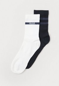 Két pár zokni: az egyik fehér ribbelt mintával és sötétkék csíkkal, a másik egyszínű fekete. Mindkettőn "HUGO" logó található.