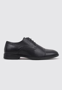 Zapato de vestir negro de cuero con punta redonda, perforaciones brogue detalladas cerca del tobillo y suela de goma plana. Diseño de cordones.