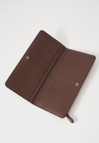 Brown leather wallet organizer featuring multiple card slots, a snap closure, and a smooth texture. Minimalist interior design.