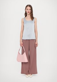 Lichtblauw mouwloos topje, brede roze broek, pastelroze handtas en crèmekleurige schoenen; soepele texturen en zachte kleuren.