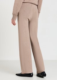 Beige gestrickte weitbeinige Hose aus strukturiertem Material, mit hoher Taille und gerader Silhouette, kombiniert mit schwarzen flachen Schuhen.