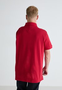 Rød polo skjorte med klassisk krage, korte ermer og avslappet passform, laget av myk bomullsstoff. Jevn tekstur, ingen synlige mønstre.