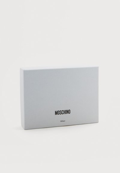 Cutie albă texturată cu un finisaj neted, cu numele mărcii "Moschino" și "Milano" tipărite cu litere negre.