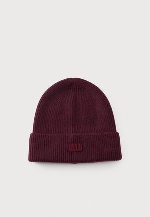 Gorro de punto acanalado color burdeos, con vuelta y un pequeño parche con el logotipo, sobre un fondo liso y claro.