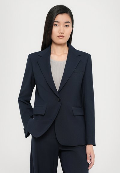 Blazer blu navy con rever a taglio, chiusura con un bottone e due tasche frontali. Tessuto liscio e strutturato, vestibilità su misura.