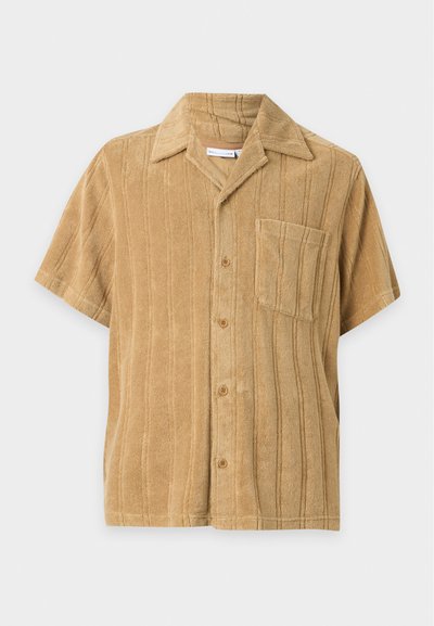 Chemise beige à manches courtes avec rayures verticales texturées, boutons sur le devant, poche poitrine et col classique sur fond uni.