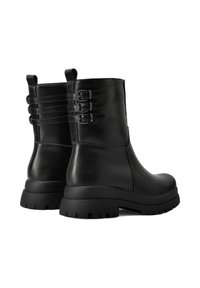 Stivaletti neri in pelle con punta arrotondata, pannelli testurizzati e tre fibbie regolabili sul retro. Suola in gomma spessa e scolpita.