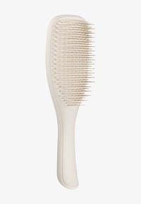 Brosse à cheveux en plastique de couleur crème pâle, avec un manche arrondi et des poils flexibles, serrés et disposés en ligne droite.