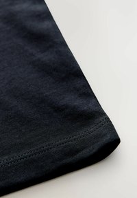 Navy Baumwoll-T-Shirt-Ecke mit glatter Textur, ausgestattet mit einem genähten Saum und einem schlichten Design.