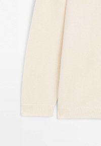 Manica di un maglione beige, realizzata in un morbido tessuto testurizzato. Presenta polsini a coste e un design pulito e semplice, senza motivi visibili.