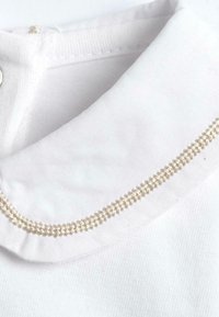 Col blanc avec une texture lisse, présentant un détail de couture en or décoratif le long du bord. Le tissu semble doux et bien fini.