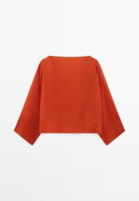 Roestoranje blouse met lange mouwen, brede mouwen en een rechte, kastige snit, gezien van achteren tegen een witte achtergrond.