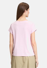 T-shirt rose à manches courtes en coton doux, avec un col rond, des manches retroussées et une coupe droite à l'ourlet. Texture lisse.