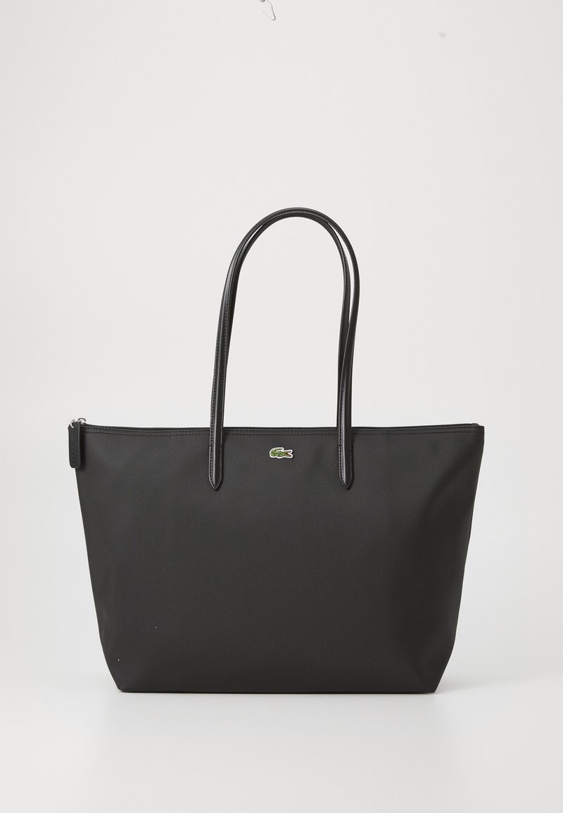 Black tote bag with two long handles, a zippered top, and a small green crocodile logo centered below the handles.